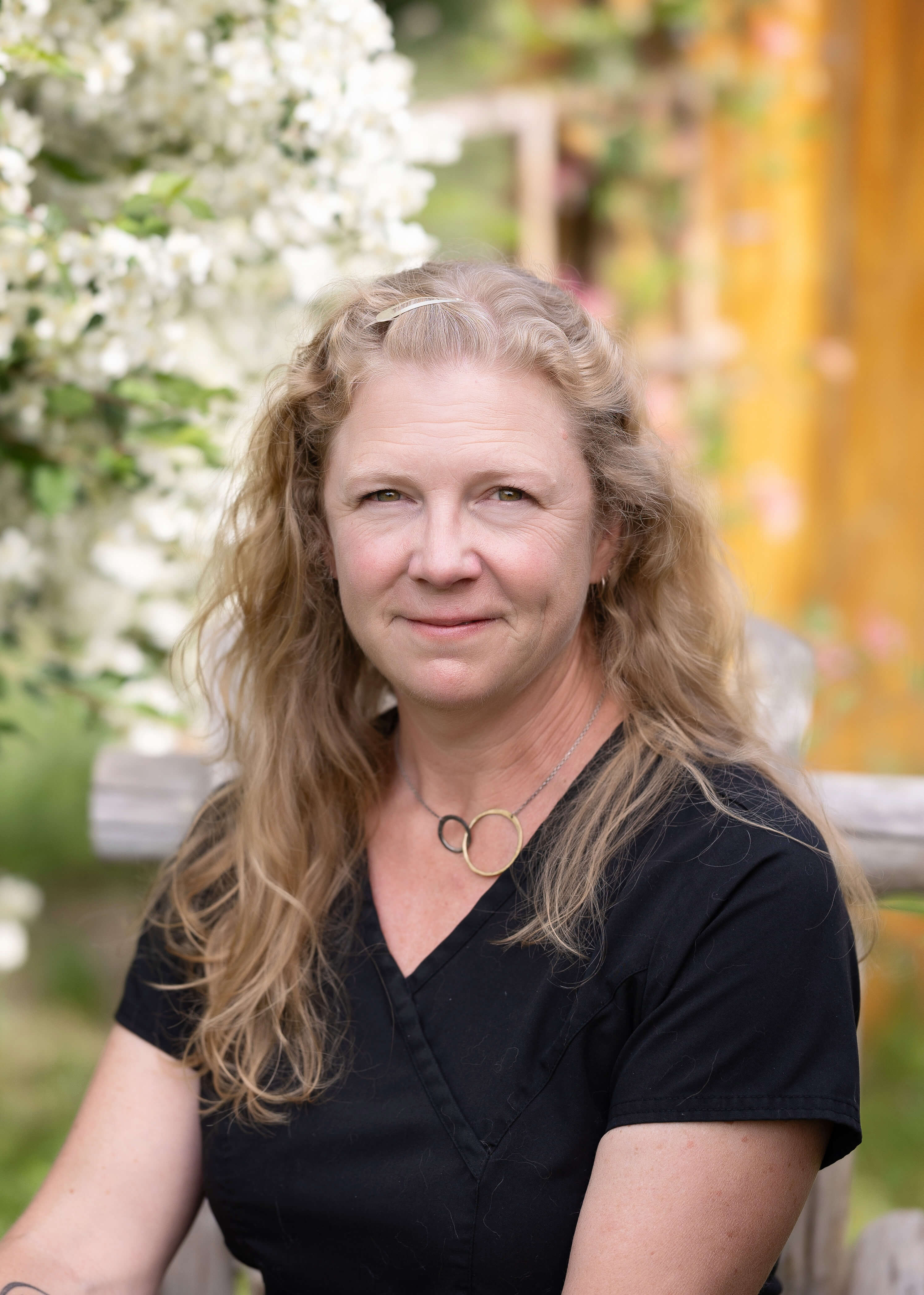 Blonde woman in black scrubs sitting in a chair outside